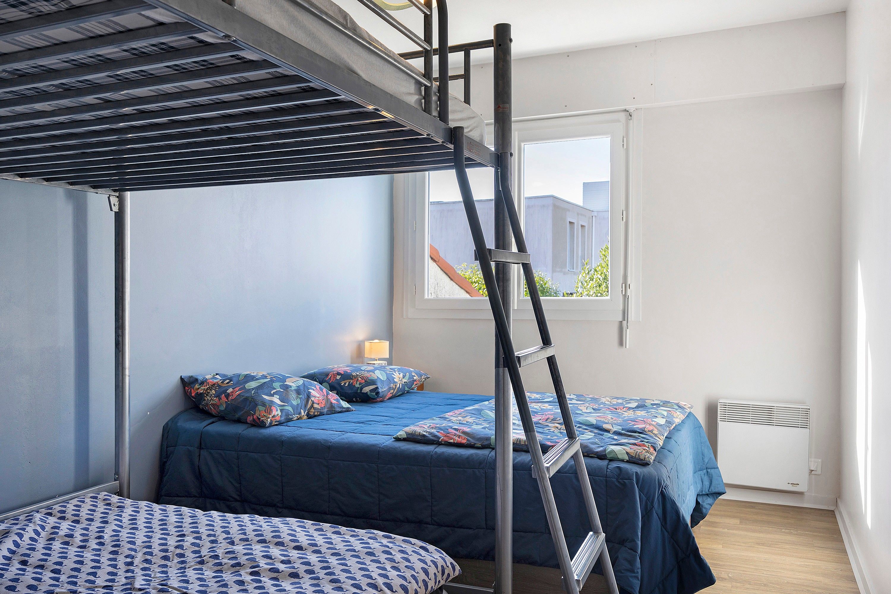 Een slaapkamer met stapelbedden, een raam en een radiator.