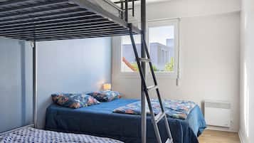 Een slaapkamer met stapelbedden, een raam en een radiator.