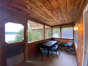 A wooden deck with a table and chairs, overlooking a body of water. - Cozy lakefront chalet, breathtaking views, high-speed wifi (Sainte-Thérèse-de-la-Gatineau)