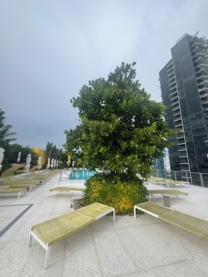 A modern outdoor area with a pool, lounge chairs, and a tall building in the background. - All new at the campy Standard Residences and ready to be enjoyed 2br/2ba condo. (Miami)