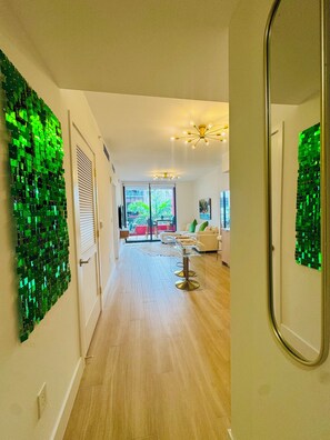 A modern interior with a hallway leading to a living area, featuring a glass table and a green mosaic wall. - All new at the campy Standard Residences and ready to be enjoyed 2br/2ba condo. (Miami)