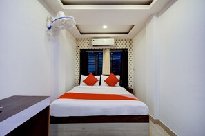 A hotel room with a bed, a nightstand, a wall-mounted air conditioner, and a window with curtains. - Hotel O ROYAL REGENCY (Kolkata)