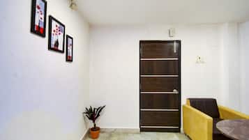 A room with a door, a potted plant, a yellow sofa, and a small table.