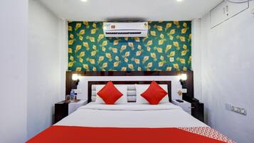 A hotel room with a bed, a nightstand, a lamp, and an air conditioning unit.