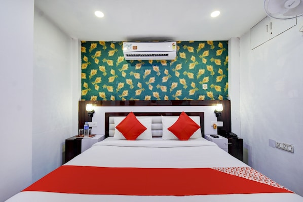 A hotel room with a bed, a nightstand, a lamp, and an air conditioning unit. - Hotel O ROYAL REGENCY (Kolkata)