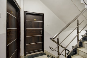 A staircase with a metal handrail and a dark wooden door with a number plate. - Hotel O ROYAL REGENCY (Kolkata)