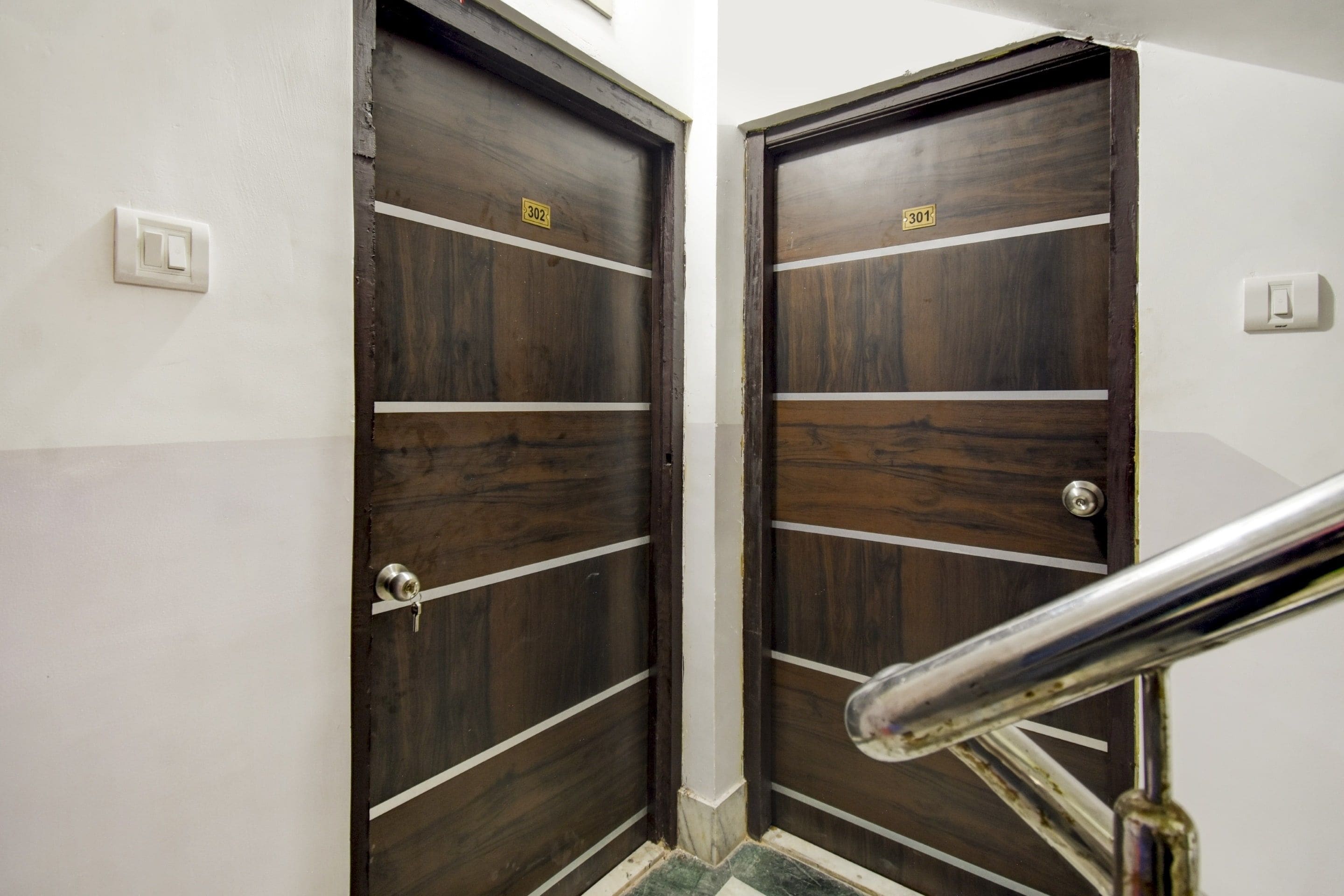 Two wooden doors with white horizontal stripes and a metal handrail in front.