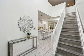 Ein modernes Interieur mit einer Treppe, einem dekorativen Spiegel und einer Konsole mit einer Vase.