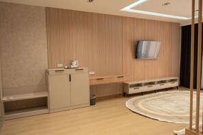 Una sala moderna con un televisor de pantalla plana montado en la pared, un mueble empotrado, un tapete redondo y un radiador.
