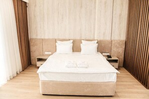 Una habitación de hotel con una cama grande, dos mesitas de noche y un cabecero de madera.