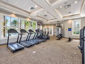 A fitness center with treadmills, weight machines, and a view of a swimming pool. - 6BR house with spa / jacuzzi near Disney (Davenport)