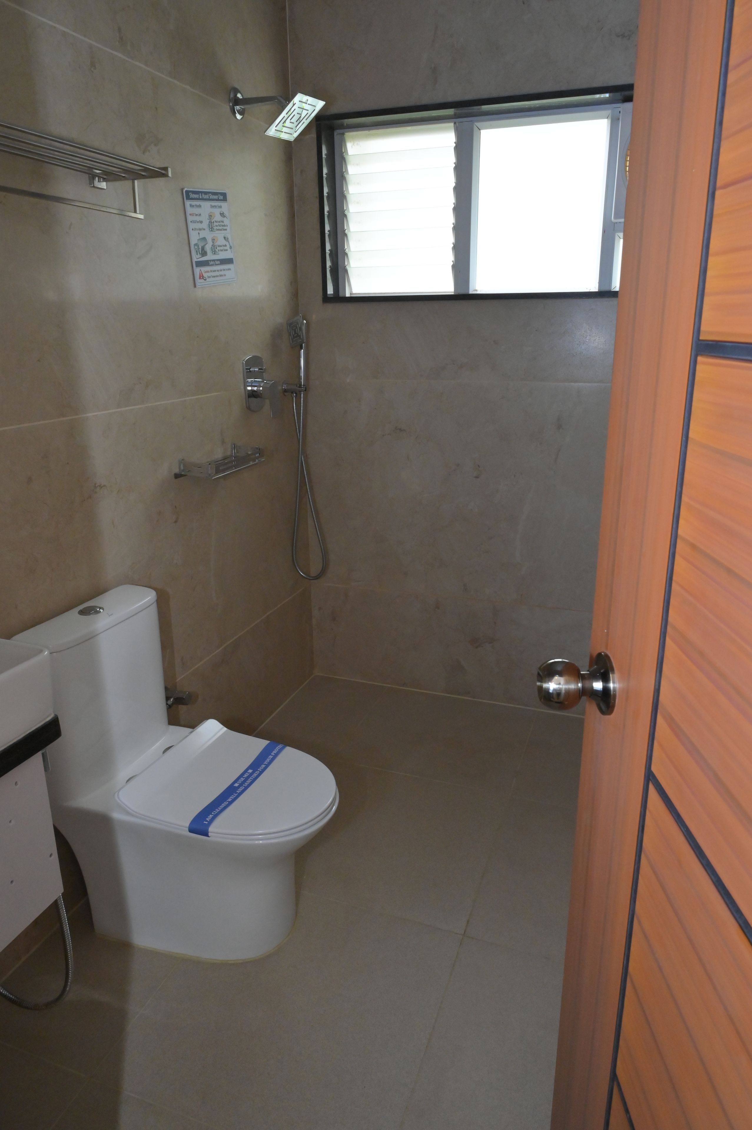 A small bathroom with a toilet, a shower, and a window.