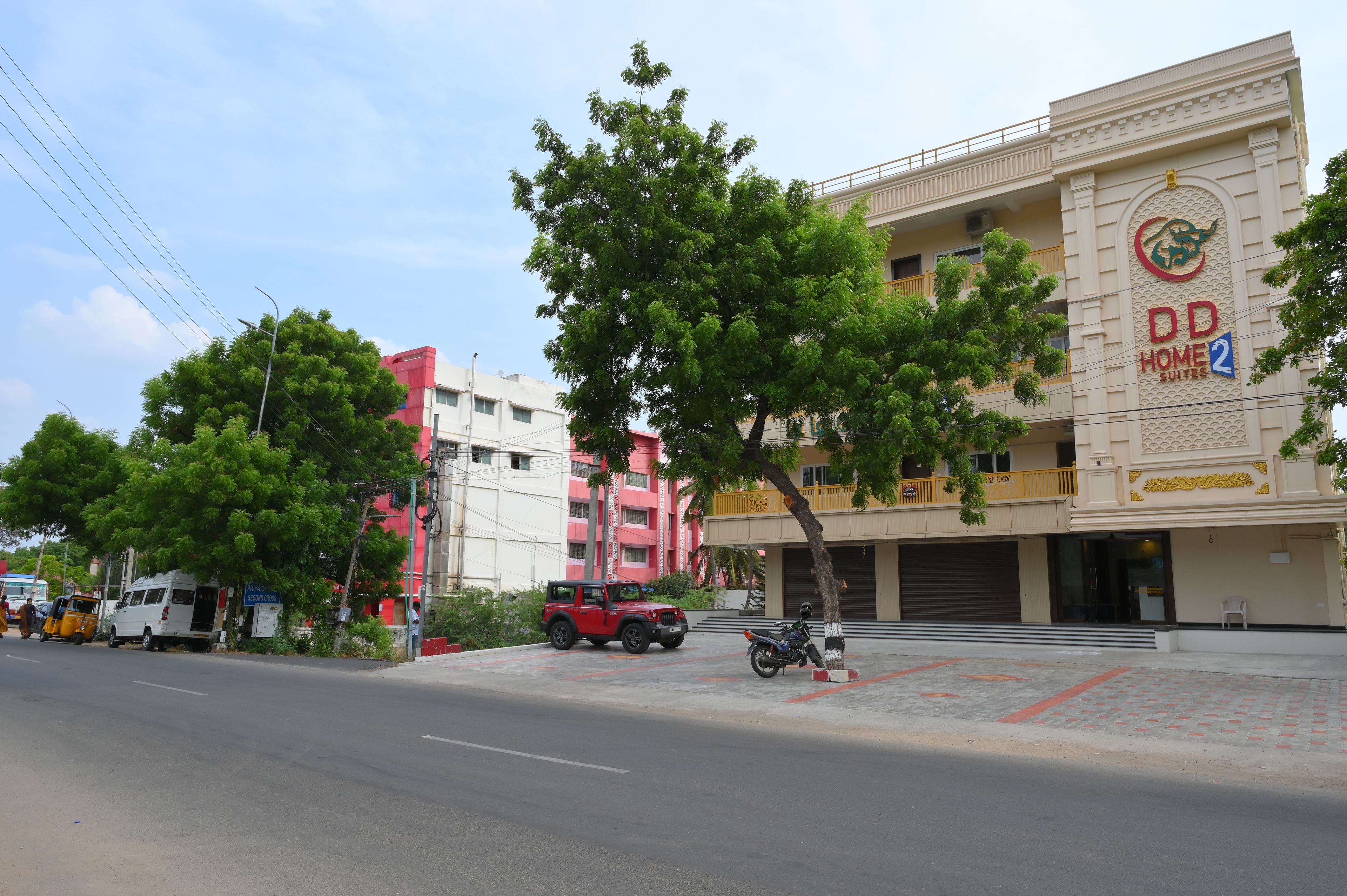 A hotel with a prominent sign, a covered outdoor area, and a street with vehicles and pedestrians.