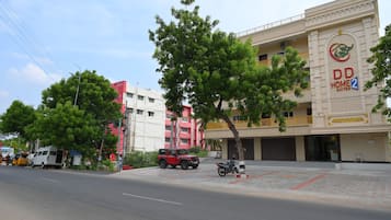 A hotel with a prominent sign, a covered outdoor area, and a street with vehicles and pedestrians.