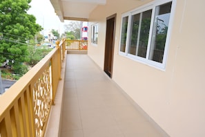 A corridor with a yellow railing, a door, and windows with a view of the street.