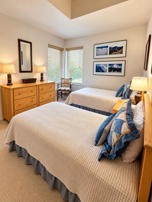 A bedroom with two beds, a dresser, a chair, and a window with blinds. - Sun Bird Townhome - pet friendly (Ketchum)