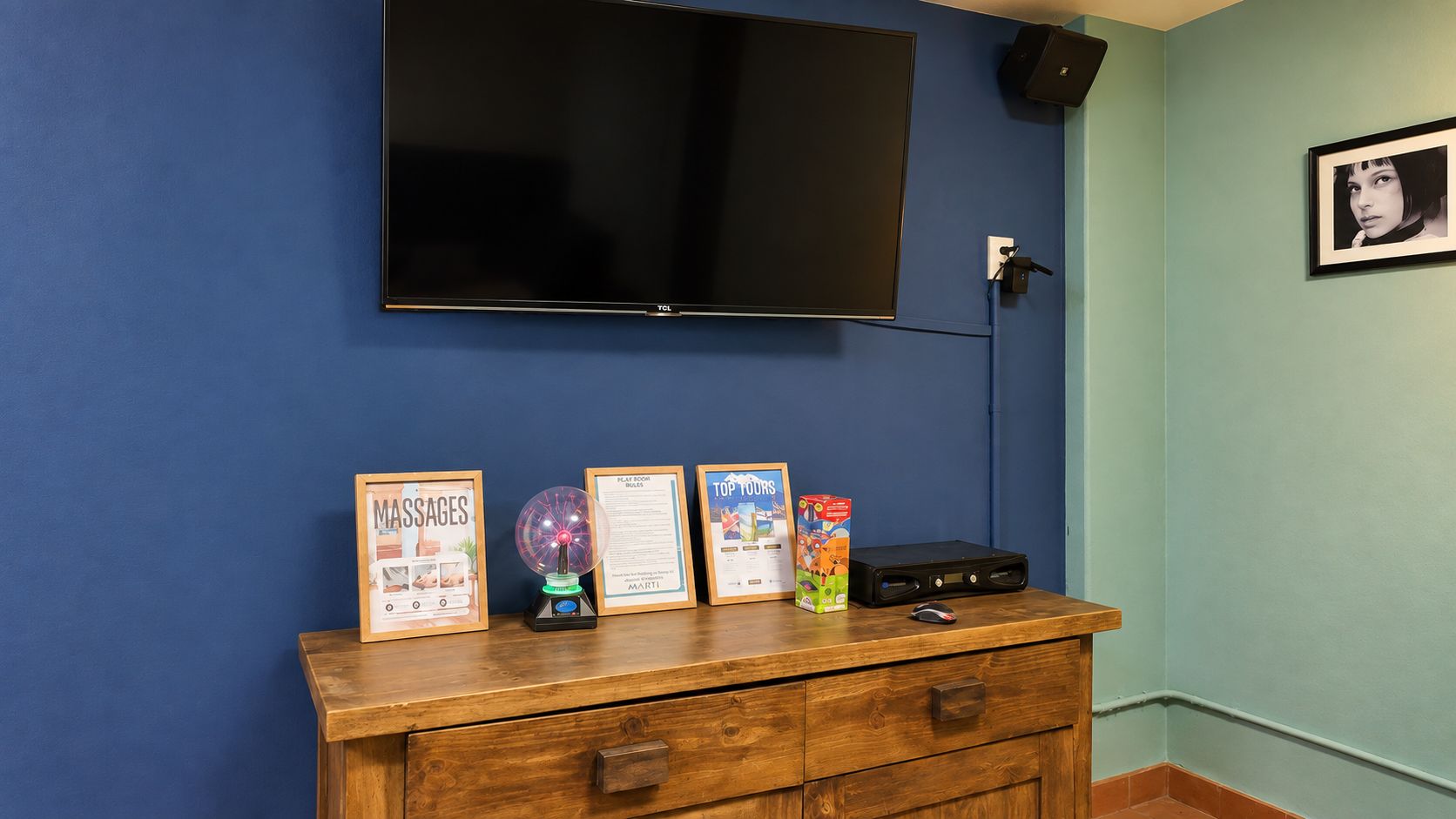 Una habitación con un televisor de pantalla plana montado en la pared, un mueble de madera con objetos enmarcados y un pequeño globo terráqueo.