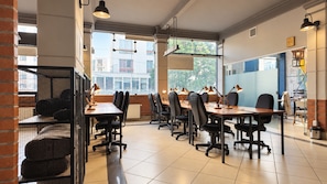 A conference room with multiple tables and chairs, large windows with views of buildings, and a brick wall on one side. - hotel martí (La Paz)