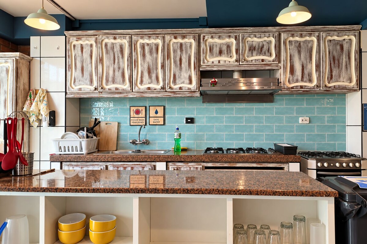 Una cocina con una isla central, electrodomésticos de acero inoxidable y un salpicadero de azulejos azules.