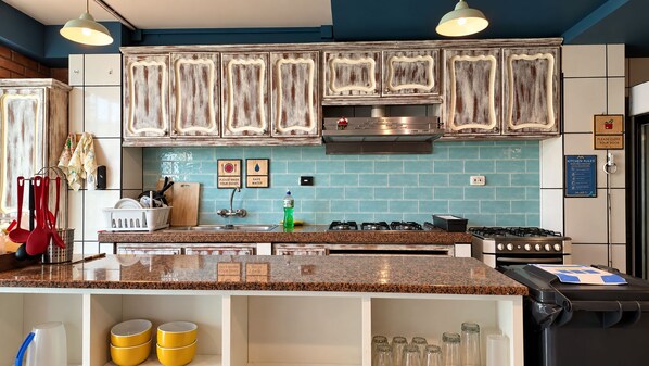 A kitchen with a central island, stainless steel appliances, and a blue tiled backsplash.