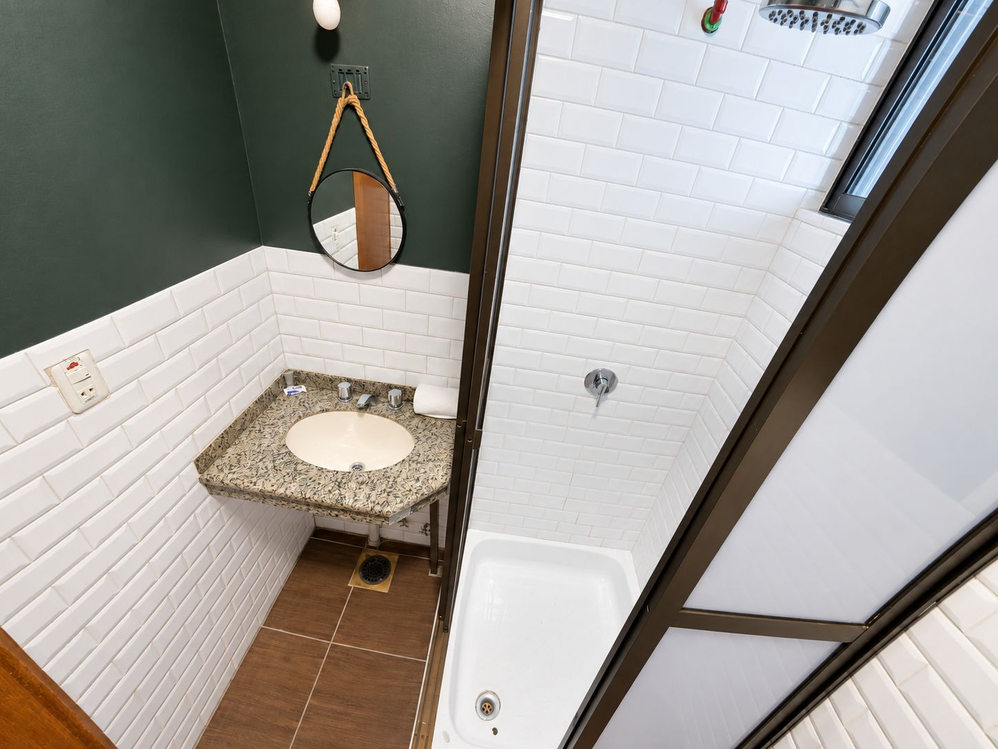 A bathroom with a white sink, a mirror, a shower, and a toilet.