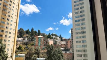Vista de uma área residencial com edifícios altos, céu azul límpido e árvores.