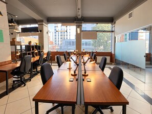 Un salón de conferencias con una larga mesa, sillas y varias lámparas.