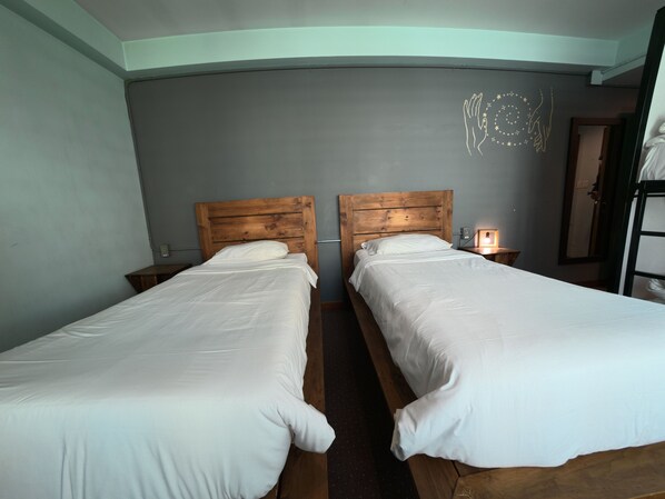A twin room with two single beds, wooden headboards, a nightstand with a lamp, and a mirror on the wall.
