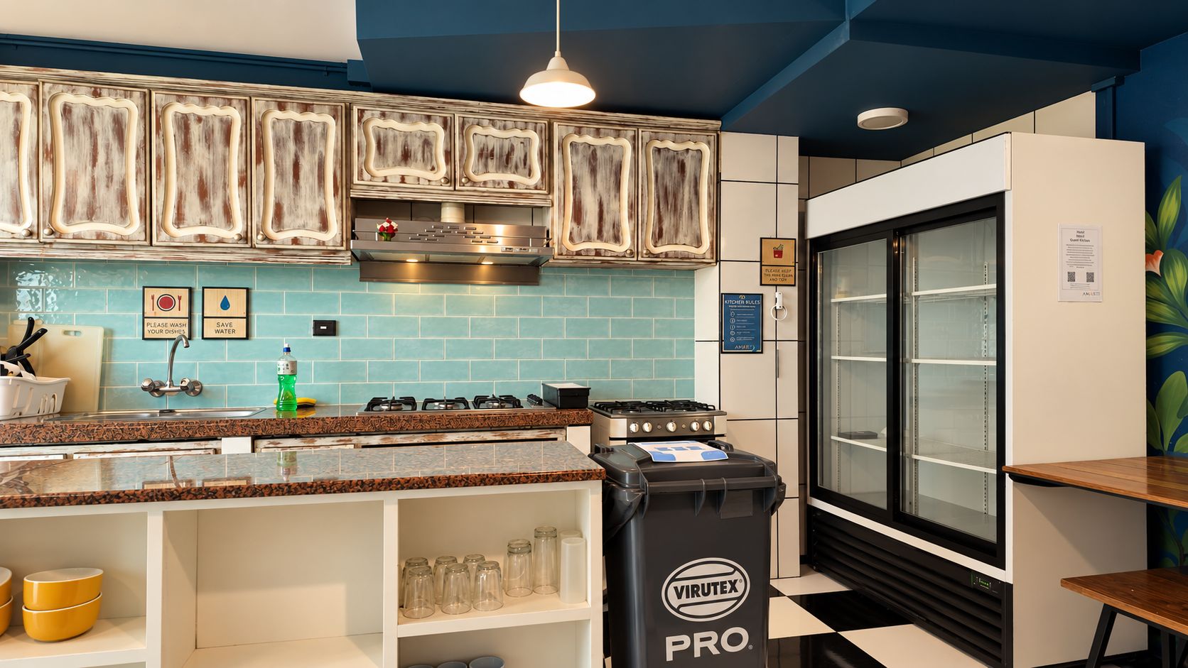 Cocina con salpicadero de azulejos azules, electrodomésticos de acero inoxidable y un cubo de basura negro con la etiqueta VIRUTEX PRO.