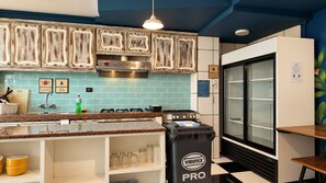 Cocina con salpicadero de azulejos azules, electrodomésticos de acero inoxidable y un cubo de basura negro con la etiqueta VIRUTEX PRO.