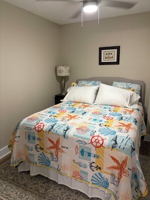 A bedroom with a bed, a nightstand, a lamp, and a framed picture on the wall.