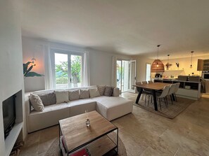 Ein modernes Wohnzimmer mit einer Eckcouch, einem Couchtisch und einem Essbereich mit Stühlen und einem Tisch.