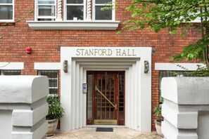 The entrance to Stanford Hall with a brick facade, a wooden door, and a fire alarm. - Stanford Escape Shared Rooftop with Harbour Views (Potts Point)