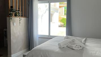 Un dormitorio con cama, ventana con cortinas, una planta y un equipo de aire acondicionado.