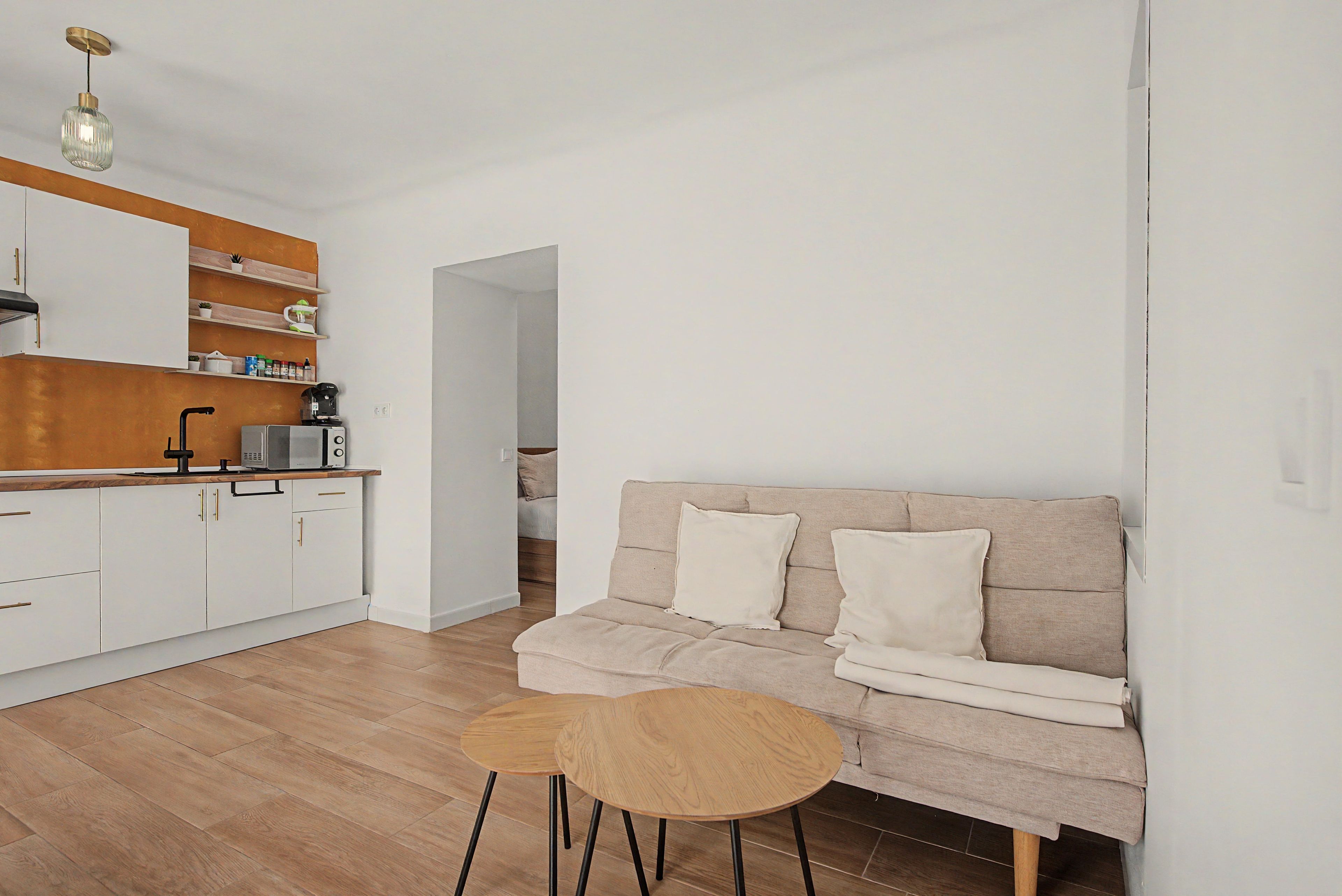 A modern kitchen with white cabinets, a wooden countertop, and a coffee machine.