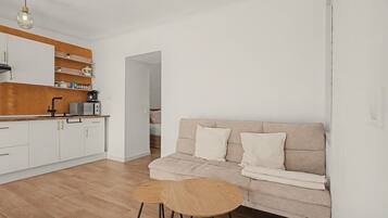 A modern kitchen with white cabinets, a wooden countertop, and a coffee machine.