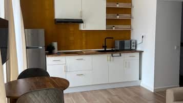 Una cocina funcional con armarios blancos, microondas integrado y encimera de madera.