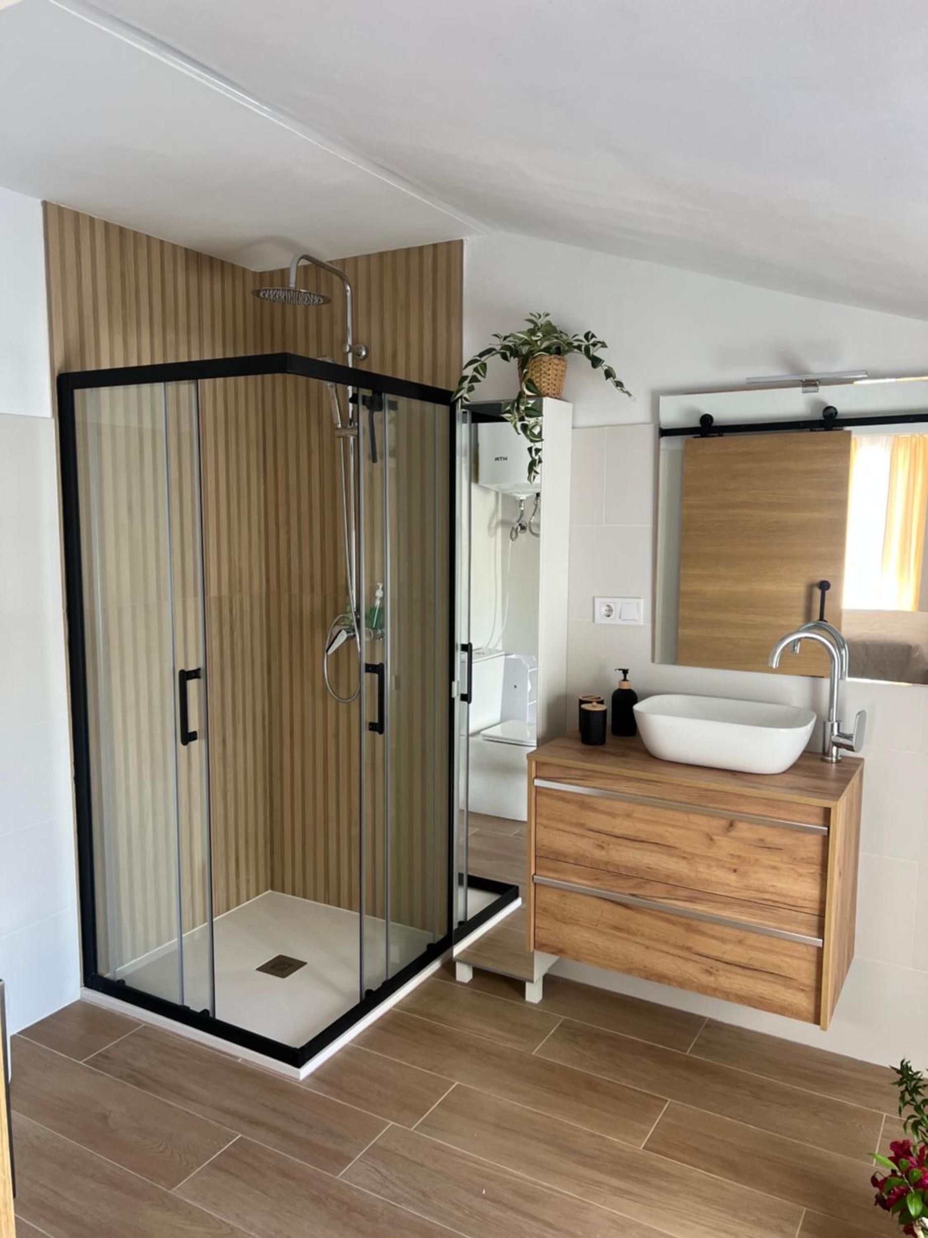 A modern bathroom with a glass-enclosed shower, a wooden vanity with a vessel sink, and a mirror above the sink.