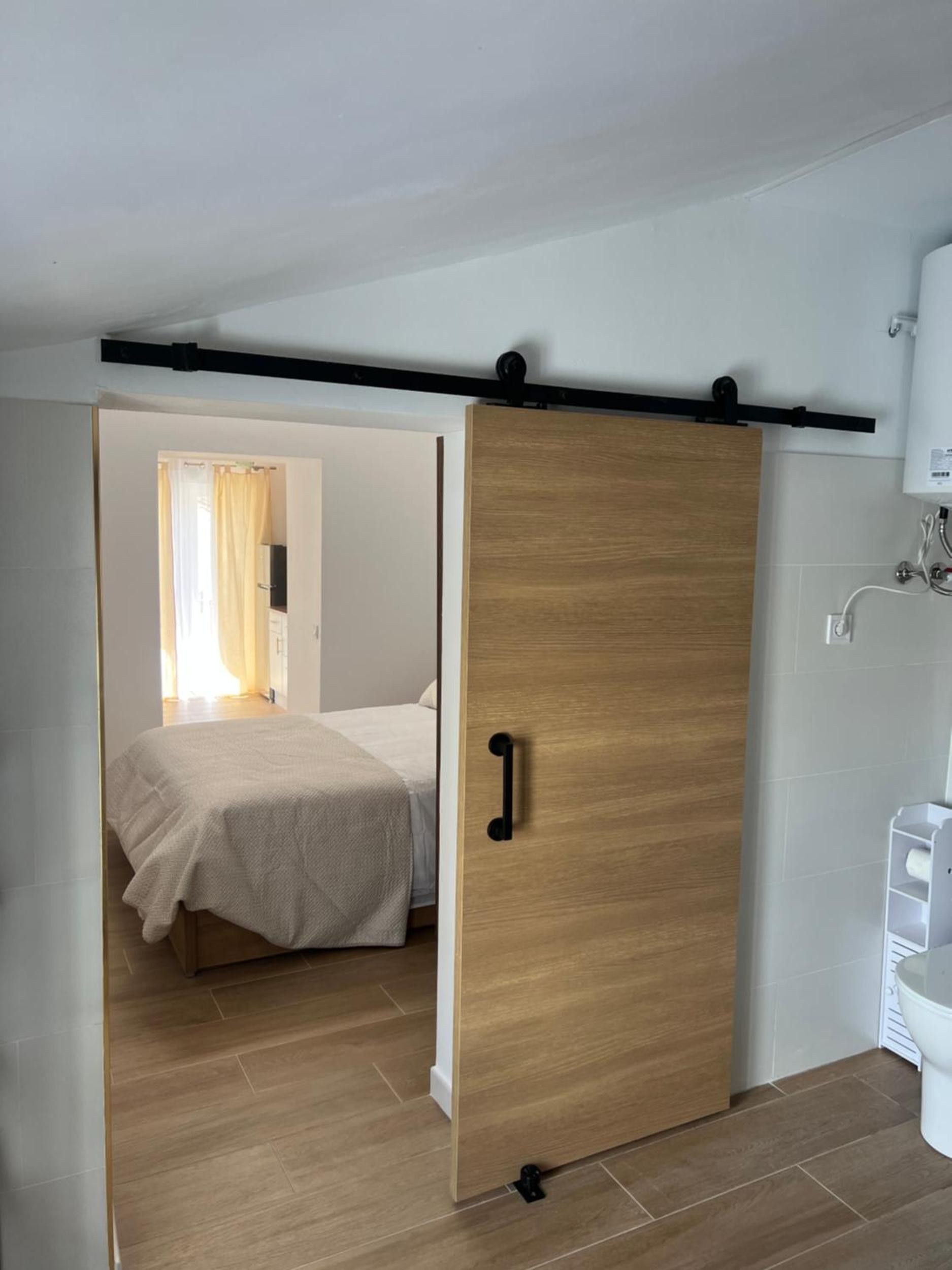 Un dormitorio con cama, un armario de madera y un baño con inodoro y lavabo.