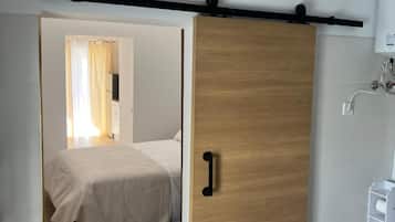 Un dormitorio con cama, un armario de madera y un baño con inodoro y lavabo.