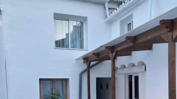 Un espacio patio con mobiliario exterior, plantas en macetas y una estructura pérgola.