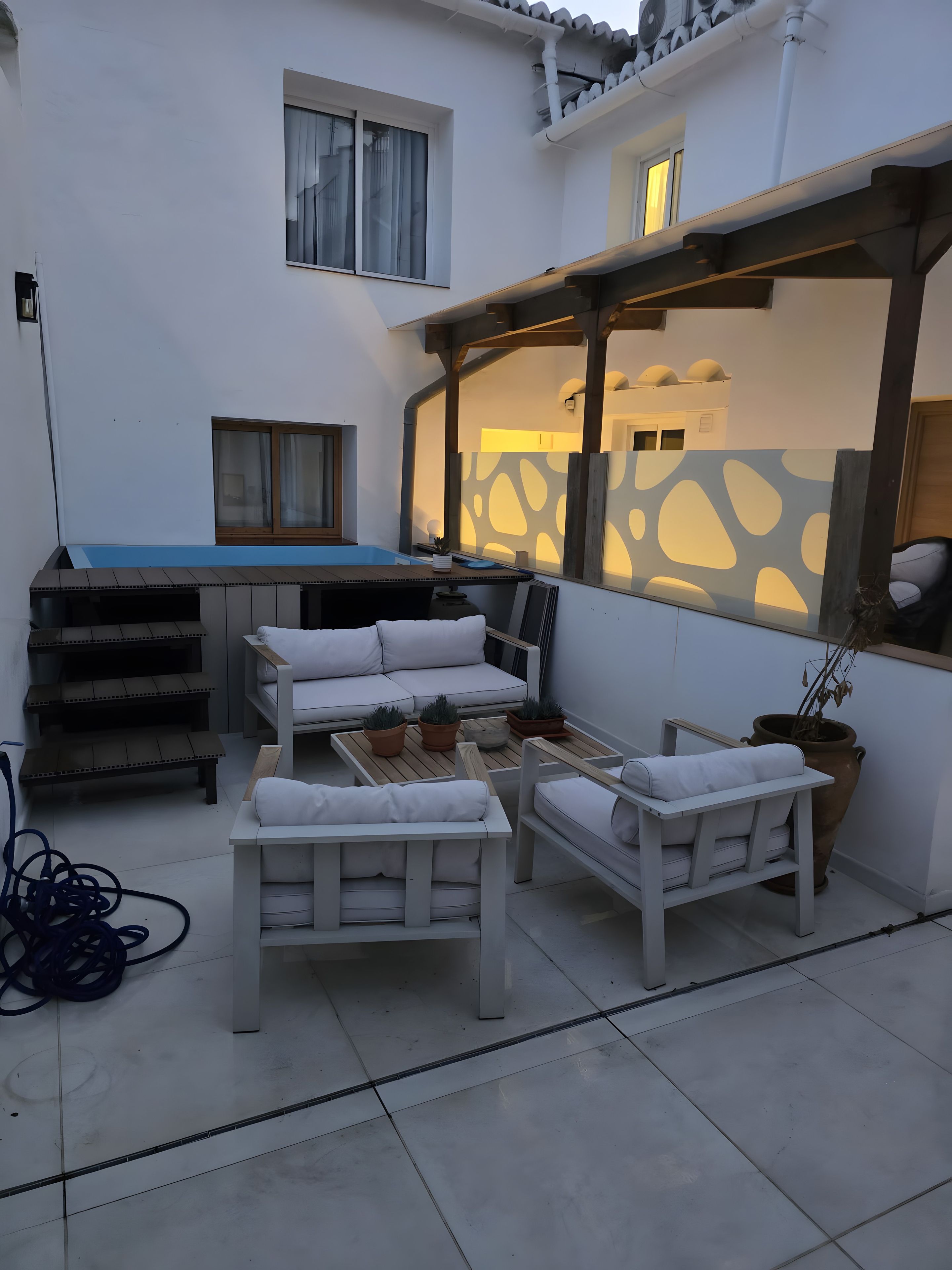 Un patio amueblado con un sofá, dos sillones, una mesita y una planta en maceta.