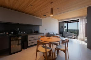 Une cuisine moderne avec un coin repas, un réfrigérateur intégré et une grande fenêtre donnant sur un paysage agréable.