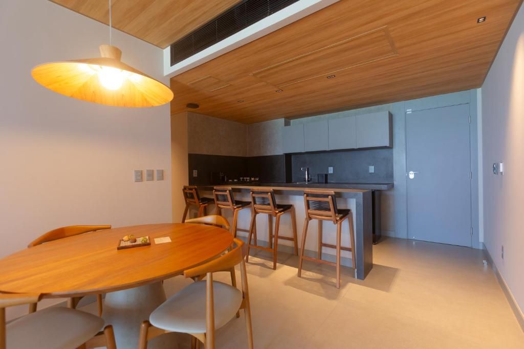 Een moderne keuken met een houten plafond, een eethoek met een ronde tafel en stoelen, en een keukeneiland met barstoelen.