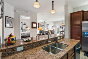Eine moderne Küche mit Granit Arbeitsplatten, Edelstahlgeräten und Pendelleuchten.