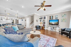 Ein modernes Wohnzimmer mit einer Couch, einem Couchtisch und einem Fernseher. Eine Treppe führt zu einer weiteren Ebene.