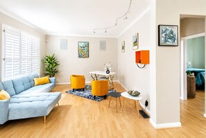 Ein Wohnzimmer mit einer Couch, Sesseln, einem Esstisch und Kunstwerken an den Wänden.