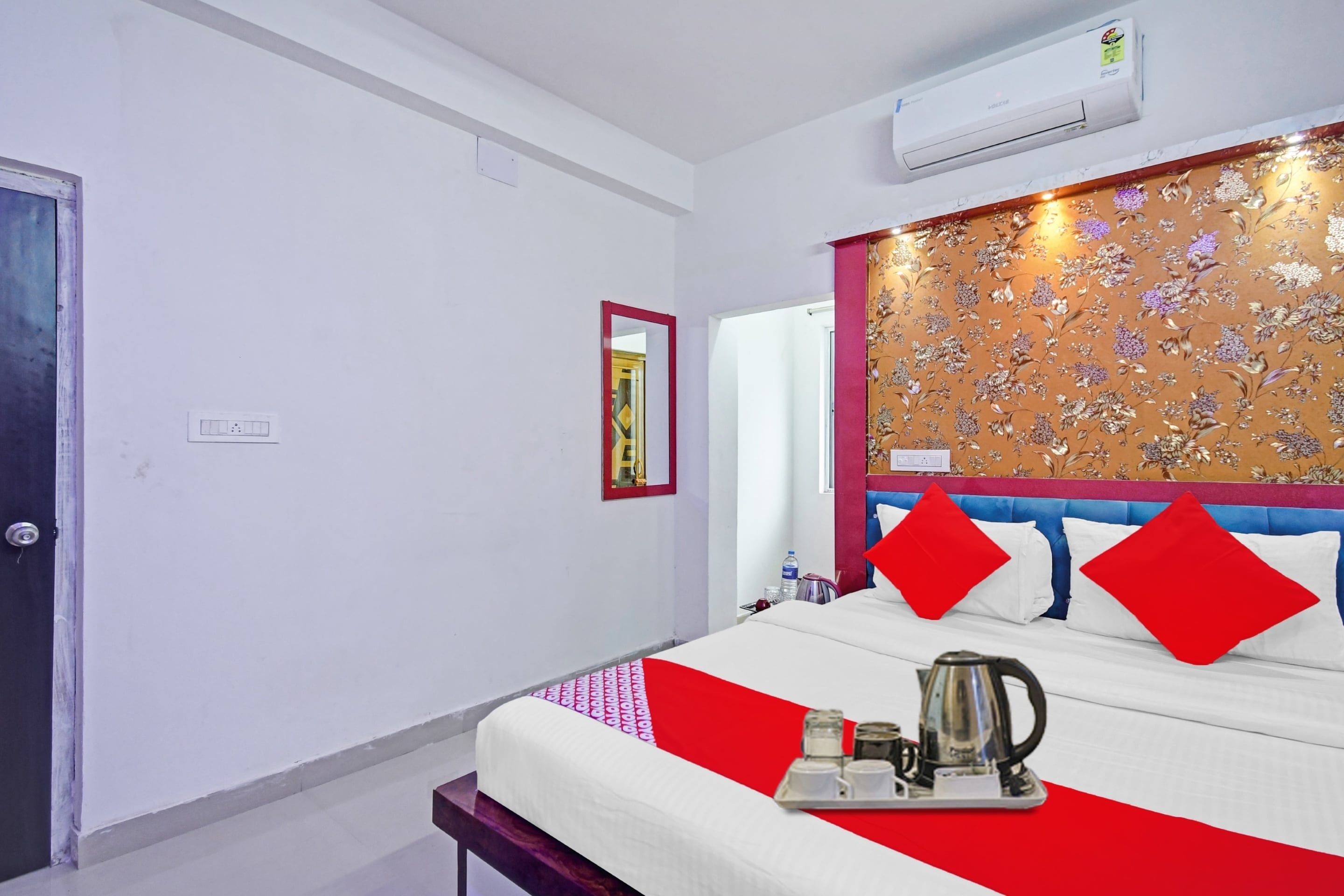 A hotel room with a bed, a bedside table, a water bottle, and a kettle.