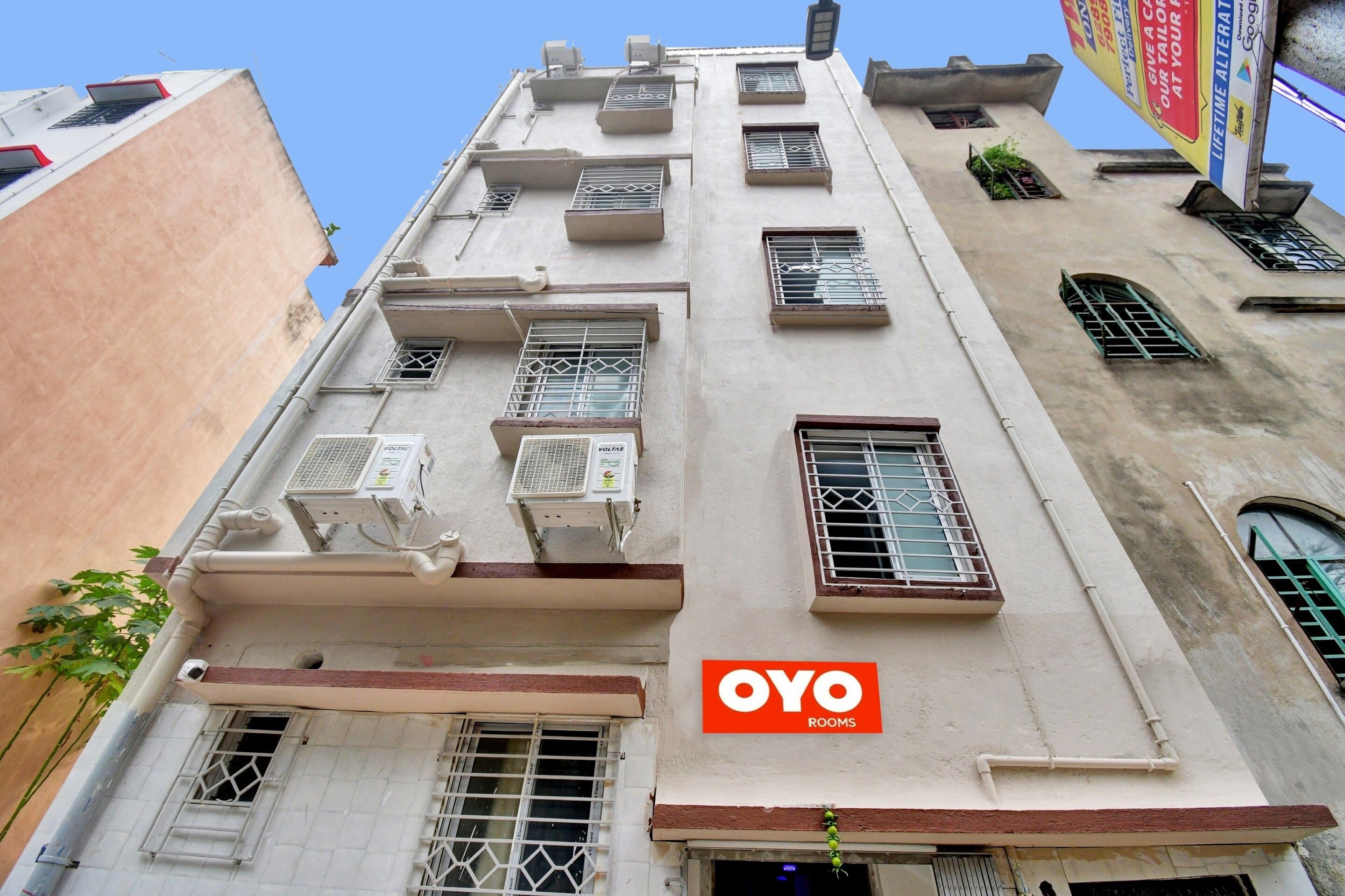A building with multiple air conditioning units, a visible entrance, and a sign for 'OYO ROOMS'.