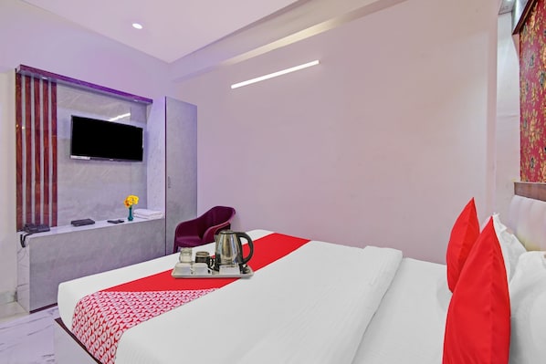 A modern hotel room with a large bed, a flat-screen TV mounted on the wall, a small seating area, and a window with curtains. - Hotel O Diamond Regency (Kolkata)